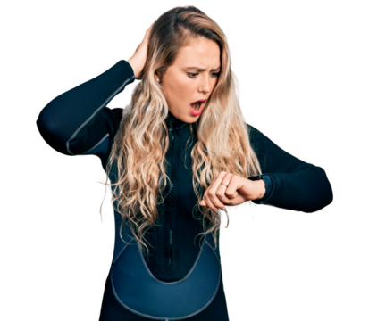 Young blonde woman wearing diver neoprene uniform looking at the watch time worried, afraid of getting late