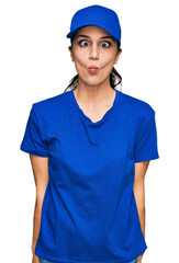 Young hispanic girl wearing delivery courier uniform making fish face with lips, crazy and comical gesture. funny expression.