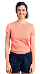 Obraz premium Young beautiful hispanic woman wearing sportswear looking positive and happy standing and smiling with a confident smile showing teeth