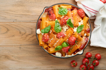 Pasta Tortiglioni with tomato sauce, baked cherry tomatoes, mozzarella and parmesan cheese, basil on old rustic table background. Traditional Italian cuisine. Example Italian food for article Top view