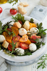Tuscan Panzanella. Cherry Tomatoes salad with arugula, basil, mozzarella and bread crackers on white bowl. Traditional italian salad. Mediterranean healthy food and cuisine.