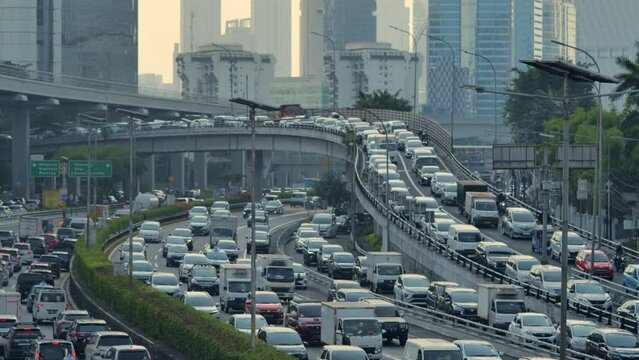 Many vehicles pass by in heavy traffic and are jammed on Jakarta's urban roads and bridges. Depicts fatigue on the road after work, chaos, and heavy pollution. Shot in afternoon.