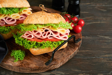 Sandwich. Tasty sandwich with ham or bacon, cheese, tomatoes, lettuce and grain bread on dark backgrounds. Delicious club sandwich or school lunch, breakfast or snack.