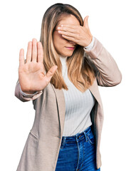Obraz na płótnie Canvas Young blonde woman wearing business shirt and glasses covering eyes with hands and doing stop gesture with sad and fear expression. embarrassed and negative concept.