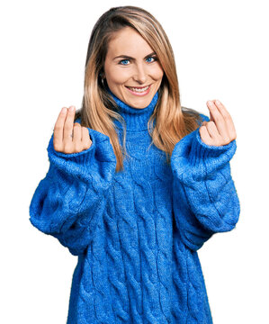 Young blonde woman wearing casual sweater doing money gesture with hands, asking for salary payment, millionaire business