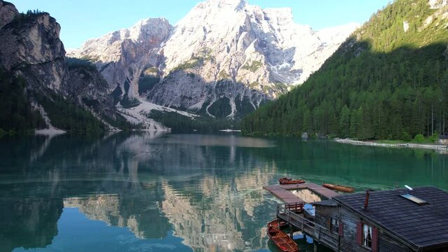 Upward revealing reflected mountain and wooden boats in Lago di Braies. Aerial