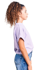 Beautiful kid girl with curly hair wearing casual clothes looking to side, relax profile pose with...