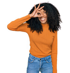 Young african american girl wearing casual clothes doing ok gesture with hand smiling, eye looking through fingers with happy face.