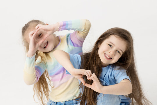 Group portrait of kids girls friends on white studio background. Happy children, cute girls hugging and having fun in carnival glasses. funny faces. Showing the shape of a heart