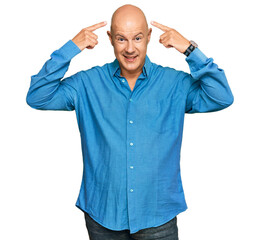 Fototapeta premium Middle age bald man wearing casual clothes smiling pointing to head with both hands finger, great idea or thought, good memory
