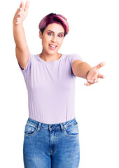 Fototapeta na wymiar Young beautiful woman with pink hair wearing casual clothes looking at the camera smiling with open arms for hug. cheerful expression embracing happiness.