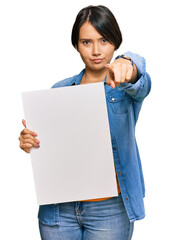 Beautiful young woman with short hair holding blank empty banner pointing with finger to the camera and to you, confident gesture looking serious