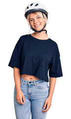 Young beautiful blonde woman wearing bike helmet looking positive and happy standing and smiling with a confident smile showing teeth