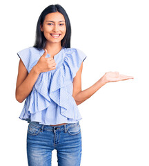 Young beautiful latin girl wearing casual clothes showing palm hand and doing ok gesture with thumbs up, smiling happy and cheerful