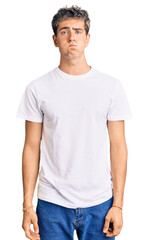 Young handsome man wearing casual white tshirt puffing cheeks with funny face. mouth inflated with air, crazy expression.