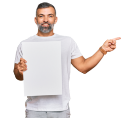 Middle age handsome man holding blank empty banner smiling happy pointing with hand and finger to the side