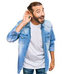 Attractive man with long hair and beard wearing casual denim jacket smiling with hand over ear listening an hearing to rumor or gossip. deafness concept.