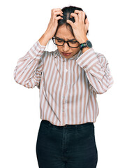 Young hispanic girl wearing casual clothes and glasses suffering from headache desperate and stressed because pain and migraine. hands on head.