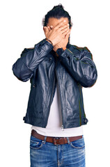 Young arab man wearing casual leather jacket covering eyes and mouth with hands, surprised and shocked. hiding emotion