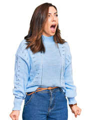 Young brunette woman wearing casual winter sweater angry and mad screaming frustrated and furious, shouting with anger. rage and aggressive concept.