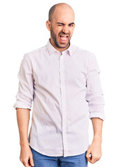 Young handsome man wearing elegant shirt winking looking at the camera with sexy expression, cheerful and happy face.
