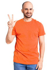 Young handsome man wering casual t shirt showing and pointing up with fingers number three while smiling confident and happy.