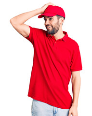 Young handsome man with beard wearing delivery uniform smiling confident touching hair with hand up gesture, posing attractive and fashionable