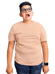 Little boy kid wearing casual clothes and glasses angry and mad screaming frustrated and furious, shouting with anger. rage and aggressive concept.