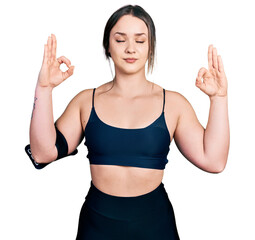 Young hispanic woman wearing sportswear relax and smiling with eyes closed doing meditation gesture with fingers. yoga concept.