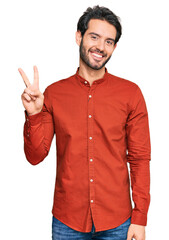 Young hispanic man wearing casual clothes showing and pointing up with fingers number two while smiling confident and happy.