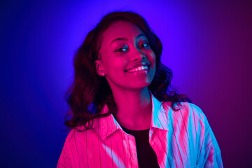 Close-up portrait of beautiful, young, african woman looking at camera, smiling against gradient...