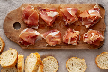 Slices of Appetizing Jamon Serrano Ready to Eat on a rustic wooden board, top view. Flat lay, overhead, from above.