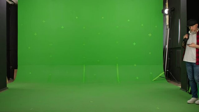Young food courier with thermal backpack standing and looking around searching for direction on a Green Screen, Chroma Key
