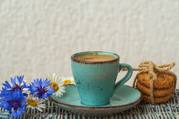 Morning blue cup of coffee, cookies, chamomile and cornflowers. Creative breakfast for Women's Day