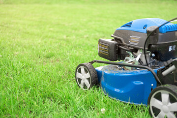 Lawn mower cutting grass. Small grass cuttings fly out of lawnmower. Grass clippings get spewed out of a mower pushed around by landscaper. Slow Motion. CloseUp. Gardener working with mower machine.