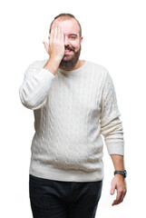 Young caucasian hipster man wearing winter sweater over isolated background covering one eye with hand with confident smile on face and surprise emotion.