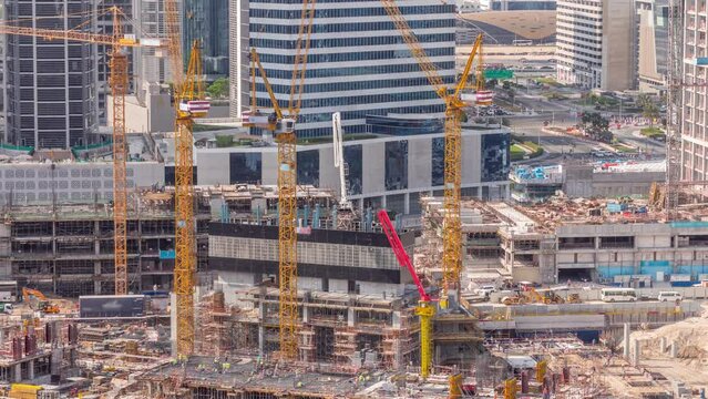 Large construction site with many working cranes timelapse. Top aerial view of big development of residential and office district in Business bay, Dubai. Workers in uniform on a reinforcement