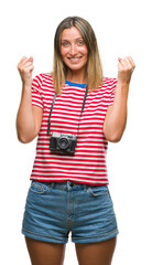 Fototapeta na wymiar Young beautiful woman taking pictures using vintage photo camera over isolated background celebrating surprised and amazed for success with arms raised and open eyes. Winner concept.