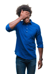 Fototapeta na wymiar Afro american man over isolated background smiling and laughing with hand on face covering eyes for surprise. Blind concept.