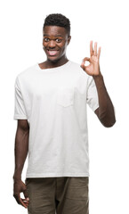 Young african american man wearing white t-shirt smiling positive doing ok sign with hand and fingers. Successful expression.