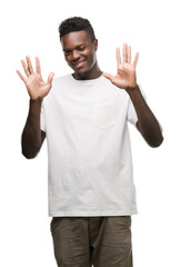 Young african american man wearing white t-shirt showing and pointing up with fingers number ten while smiling confident and happy.