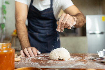 Obraz na płótnie Canvas Happy cheerful Italian chef making a fresh pizza dough on wooden table in kitchen.