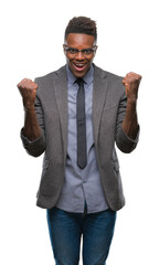 Fototapeta premium Young african american business man over isolated background celebrating surprised and amazed for success with arms raised and open eyes. Winner concept.