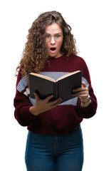 Young brunette girl reading a book wearing glasses over isolated background scared in shock with a surprise face, afraid and excited with fear expression