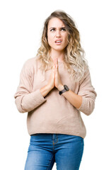 Beautiful young blonde woman wearing sweatershirt over isolated background begging and praying with hands together with hope expression on face very emotional and worried. Asking for forgiveness