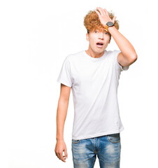 Young handsome man with afro hair wearing casual white t-shirt surprised with hand on head for...