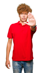 Young handsome man with afro hair wearing red t-shirt doing stop sing with palm of the hand. Warning expression with negative and serious gesture on the face.