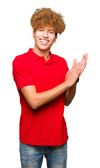 Young handsome man with afro hair wearing red t-shirt Clapping and applauding happy and joyful, smiling proud hands together