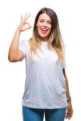 Obraz premium Young beautiful woman casual white t-shirt over isolated background smiling positive doing ok sign with hand and fingers. Successful expression.