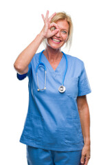 Middle age blonde nurse surgeon doctor woman over isolated background doing ok gesture with hand smiling, eye looking through fingers with happy face.